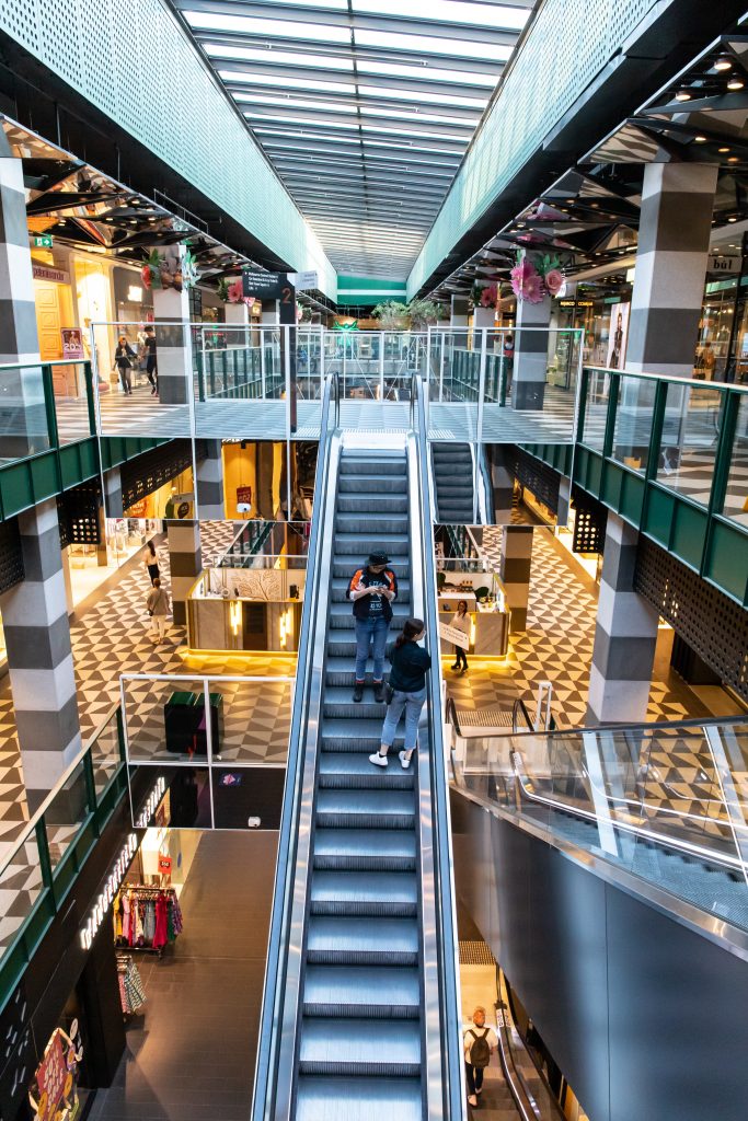 Jugendliche mit Smartphone auf Rolltreppe in Shopping Mall